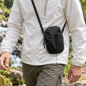 Person wearing the black EasiCyco phone pouch crossbody beside an outdoor stream